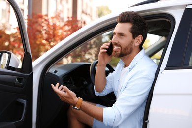 Photo of Happy man talking on smartphone in modern car