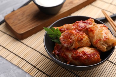 Photo of Delicious stuffed cabbage rolls cooked with tomato sauce on grey table, closeup. Space for text