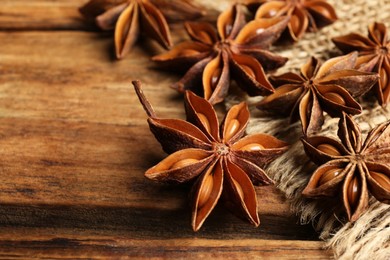 Photo of Aromatic anise stars on wooden table, closeup. Space for text