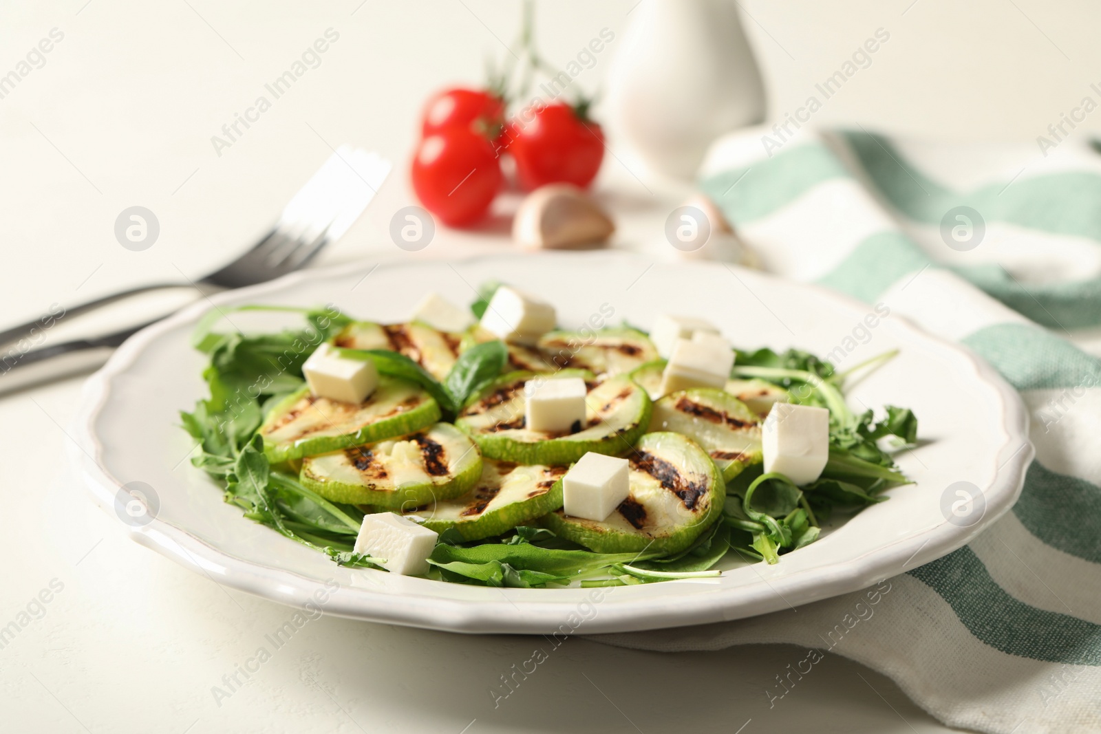 Photo of Grilled zucchini slices and feta cheese served on white table, closeup