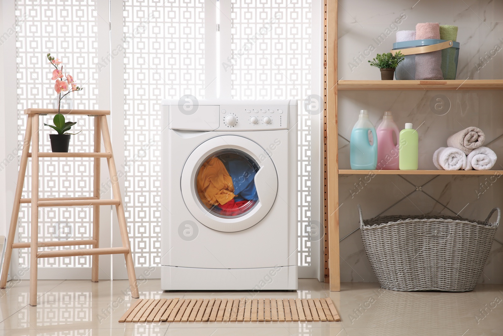 Photo of Modern washing machine with clothes in bathroom