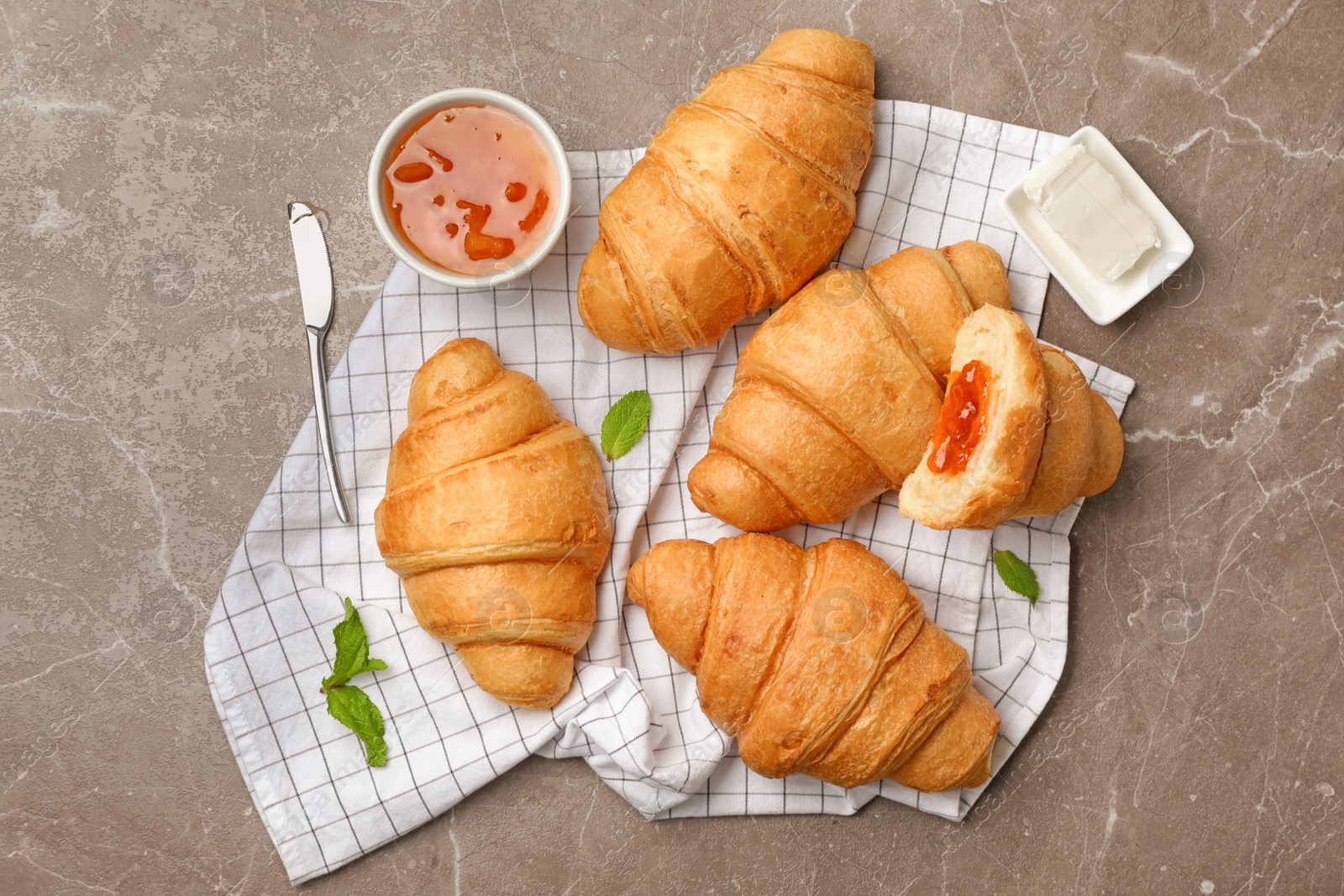 Photo of Tasty croissants with jam and butter served for breakfast on table, top view