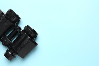 Modern binoculars on light blue background, top view. Space for text