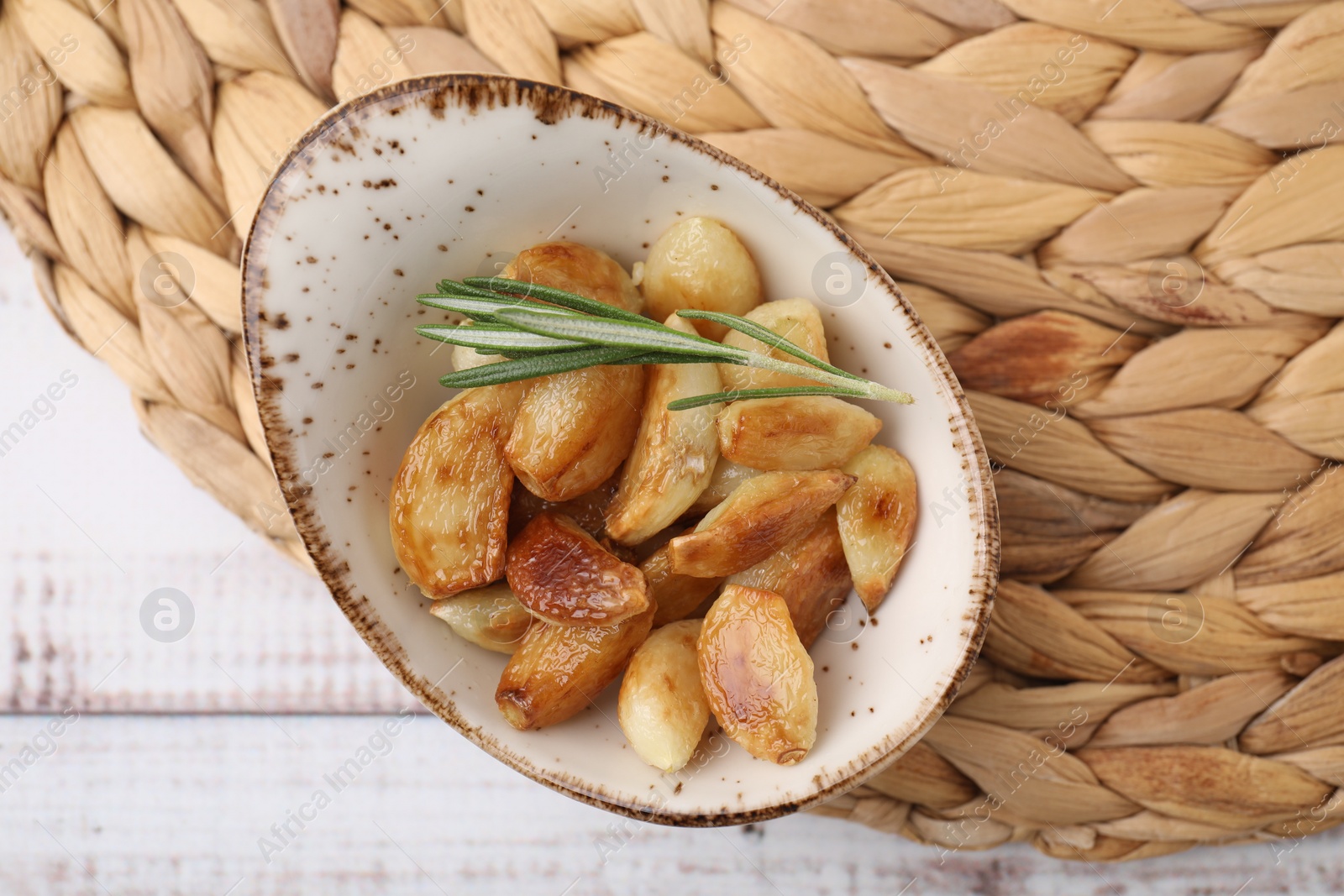 Photo of Fried garlic cloves and rosemary on table, top view