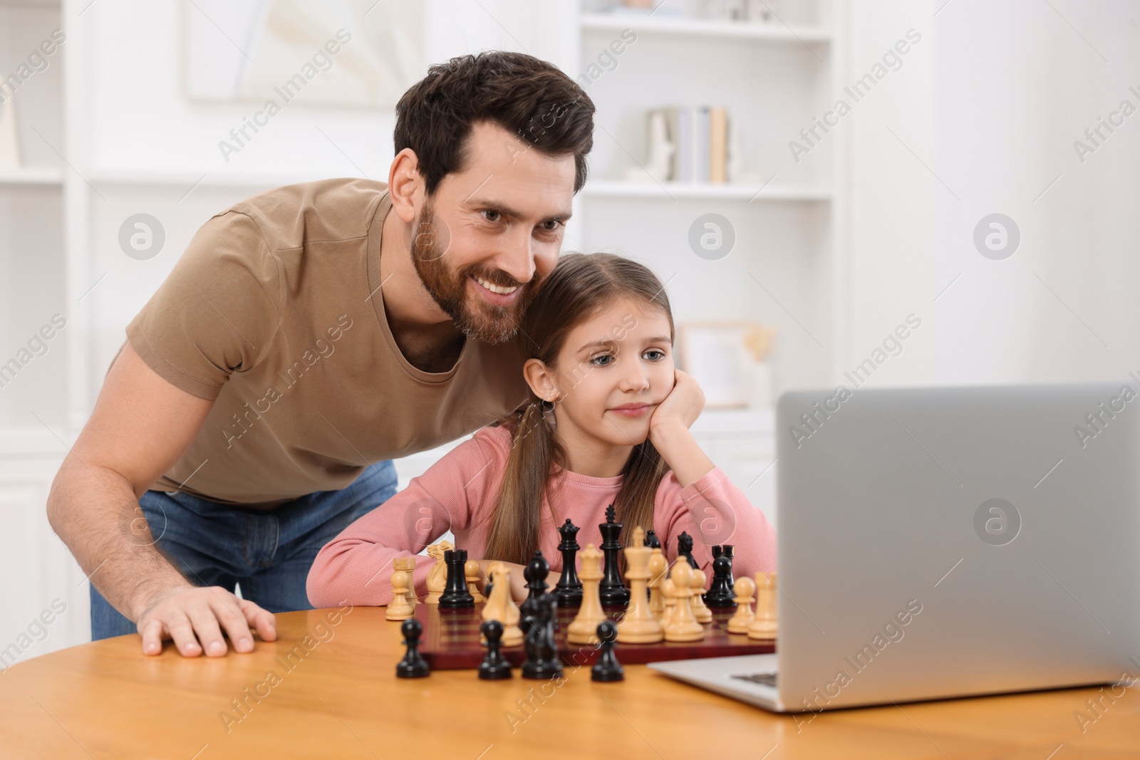 Photo of Father teaching his daughter to play chess following online lesson at home