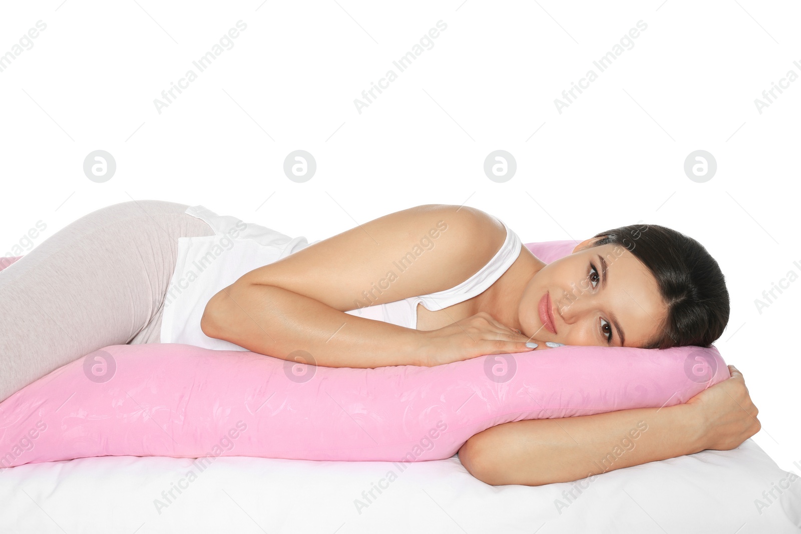 Photo of Beautiful pregnant woman lying with maternity pillow on bed against white background