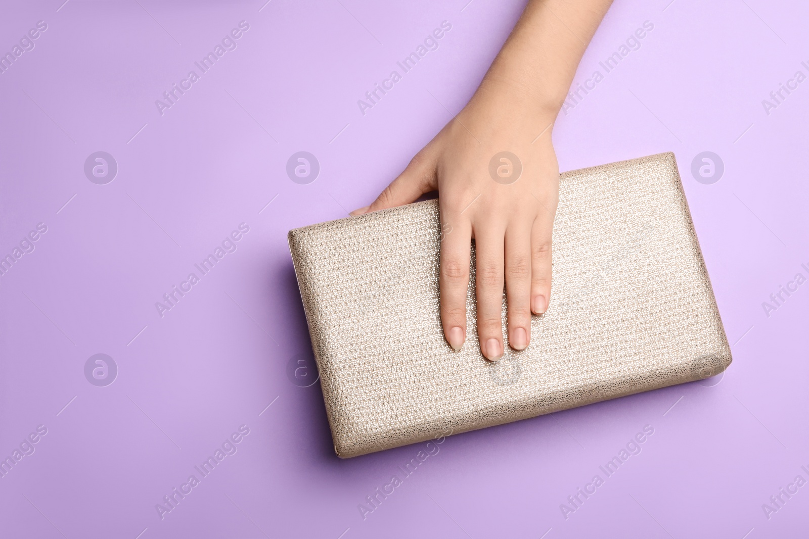 Photo of Woman holding small bag on lilac background, top view