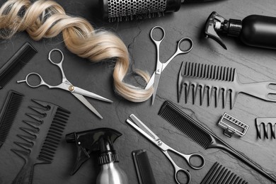 Photo of Flat lay composition of professional scissors, hair strand and other hairdresser's equipment on black table. Haircut tool