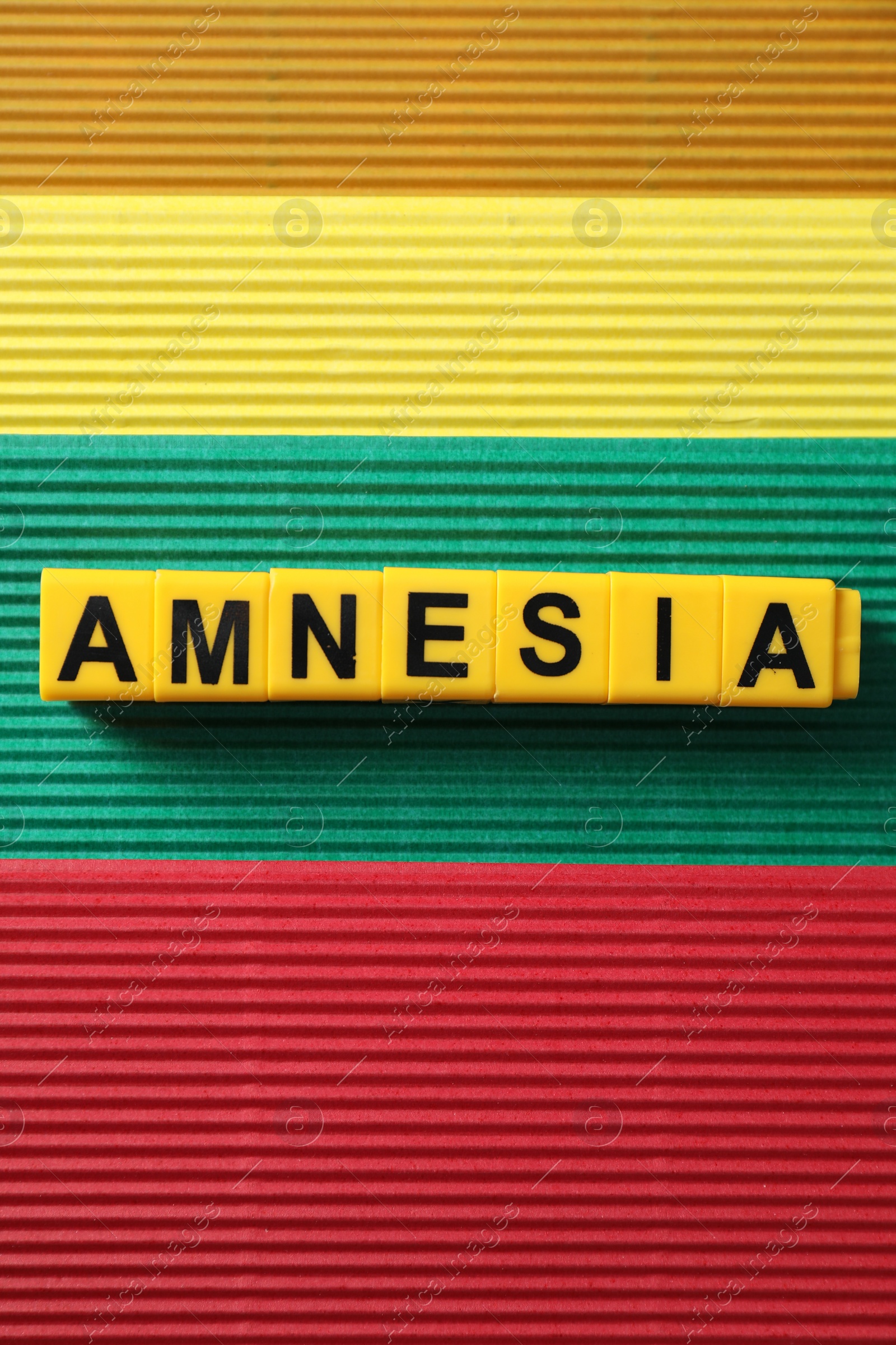Photo of Yellow cubes with word Amnesia on color background, top view