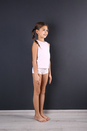 Photo of Cute little girl in underwear near dark wall