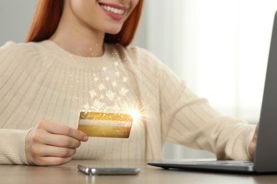 Image of Woman using laptop for online purchases at table, closeup. Shopping cart icons flying out of credit card