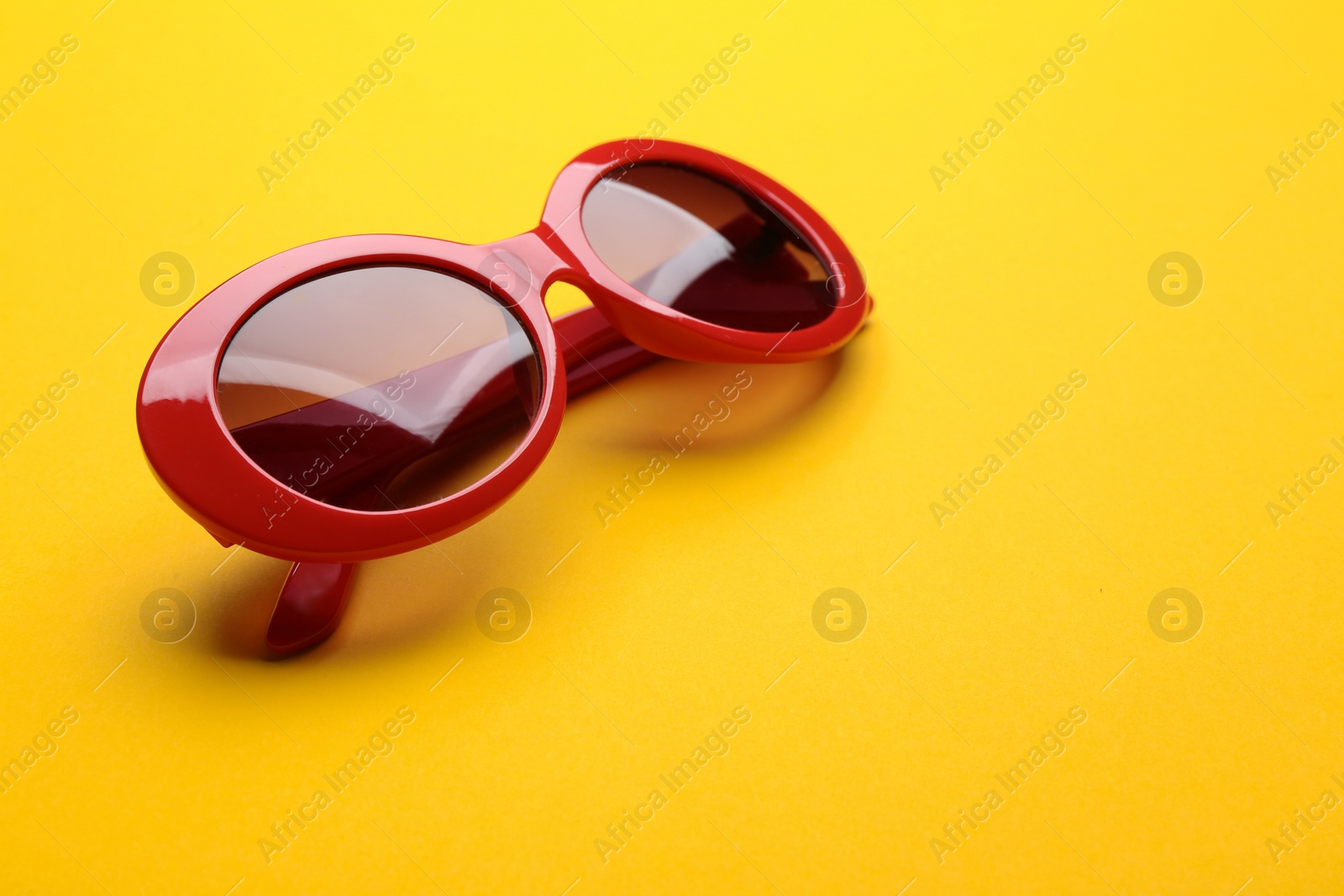 Photo of Stylish sunglasses on yellow background. Fashionable accessory