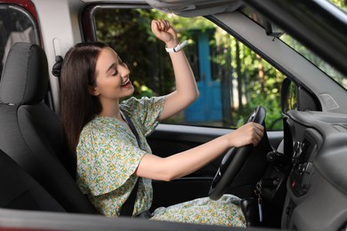 Photo of Listening to radio while driving. Beautiful young woman enjoying music in car