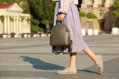 Photo of Young woman with stylish backpack on city street, closeup. Space for text