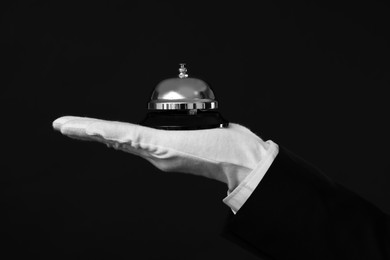 Photo of Butler holding service bell on black background, closeup