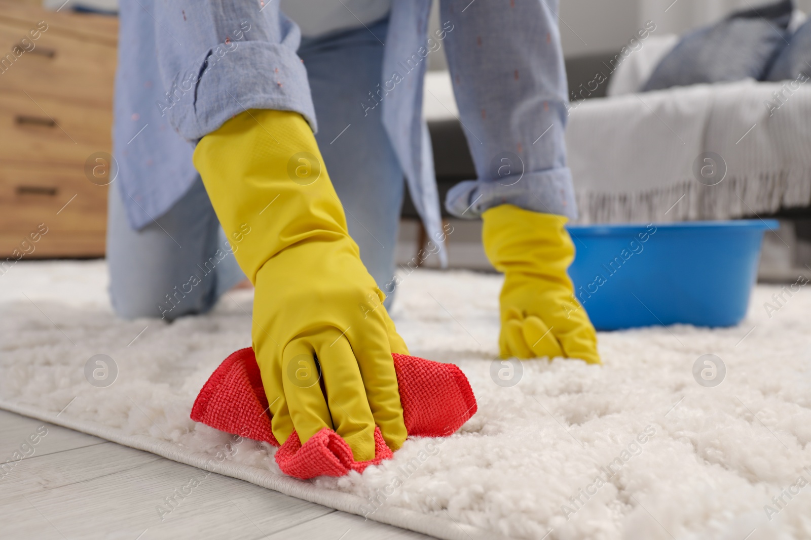 Photo of Woman in rubber gloves cleaning carpet with rag indoors, closeup