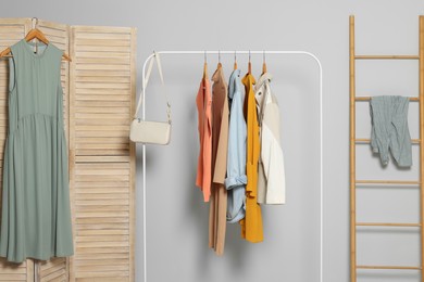 Photo of Stylish room interior with clothes rack and folding screen