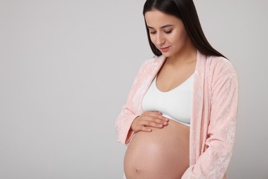 Photo of Beautiful pregnant woman in stylish comfortable underwear and robe on grey background, space for text