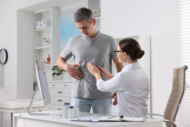 Photo of Gastroenterologist examining patient with stomach pain in clinic