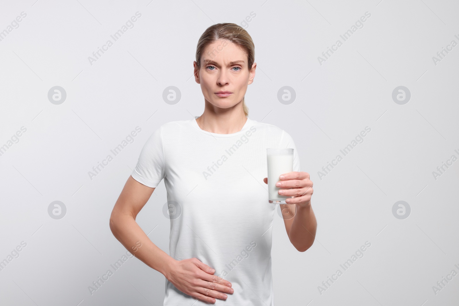 Photo of Woman with glass of milk suffering from lactose intolerance on white background