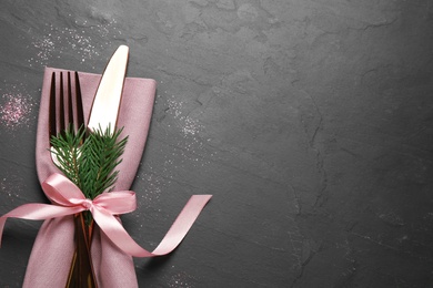 Photo of Cutlery set on black table, top view with space for text. Christmas celebration