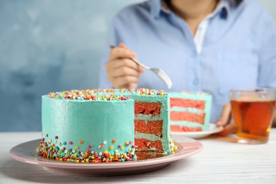 Photo of Cut fresh delicious birthday cake and blurred woman on background