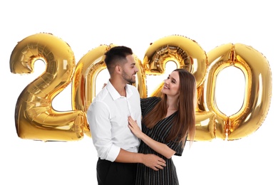 Photo of Happy young couple near golden 2020 balloons on white background. New Year celebration