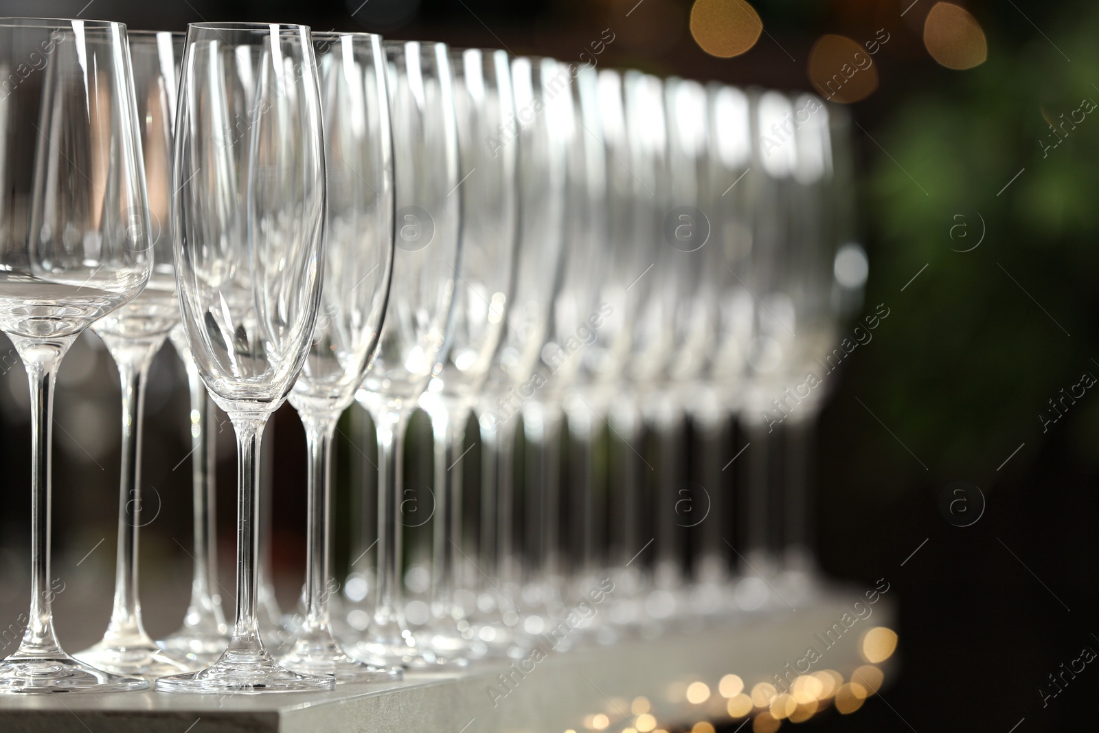Photo of Set of empty glasses on grey table against blurred background