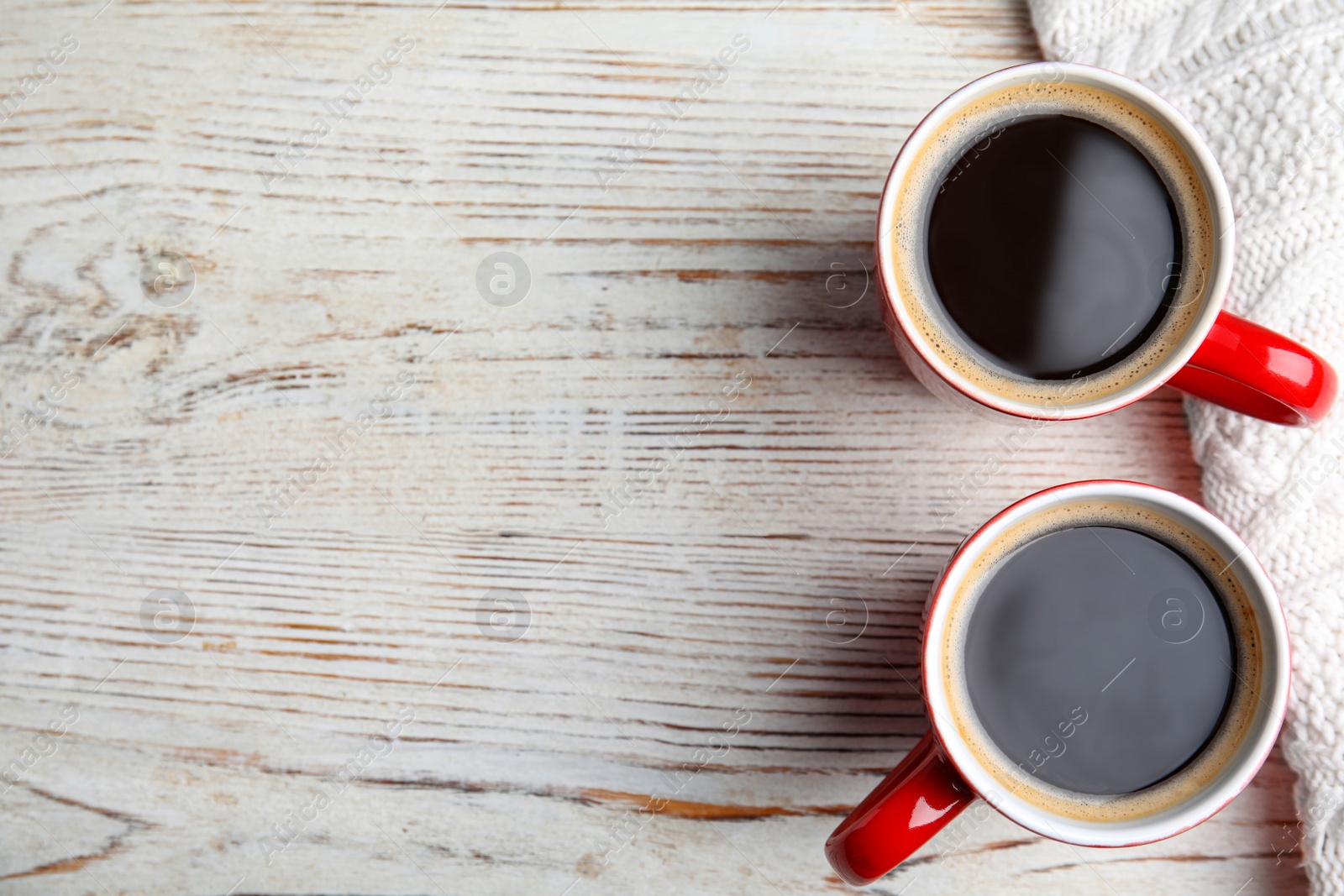 Photo of Flat lay composition cups of hot coffee and blanket on wooden background, space for text. Winter drink