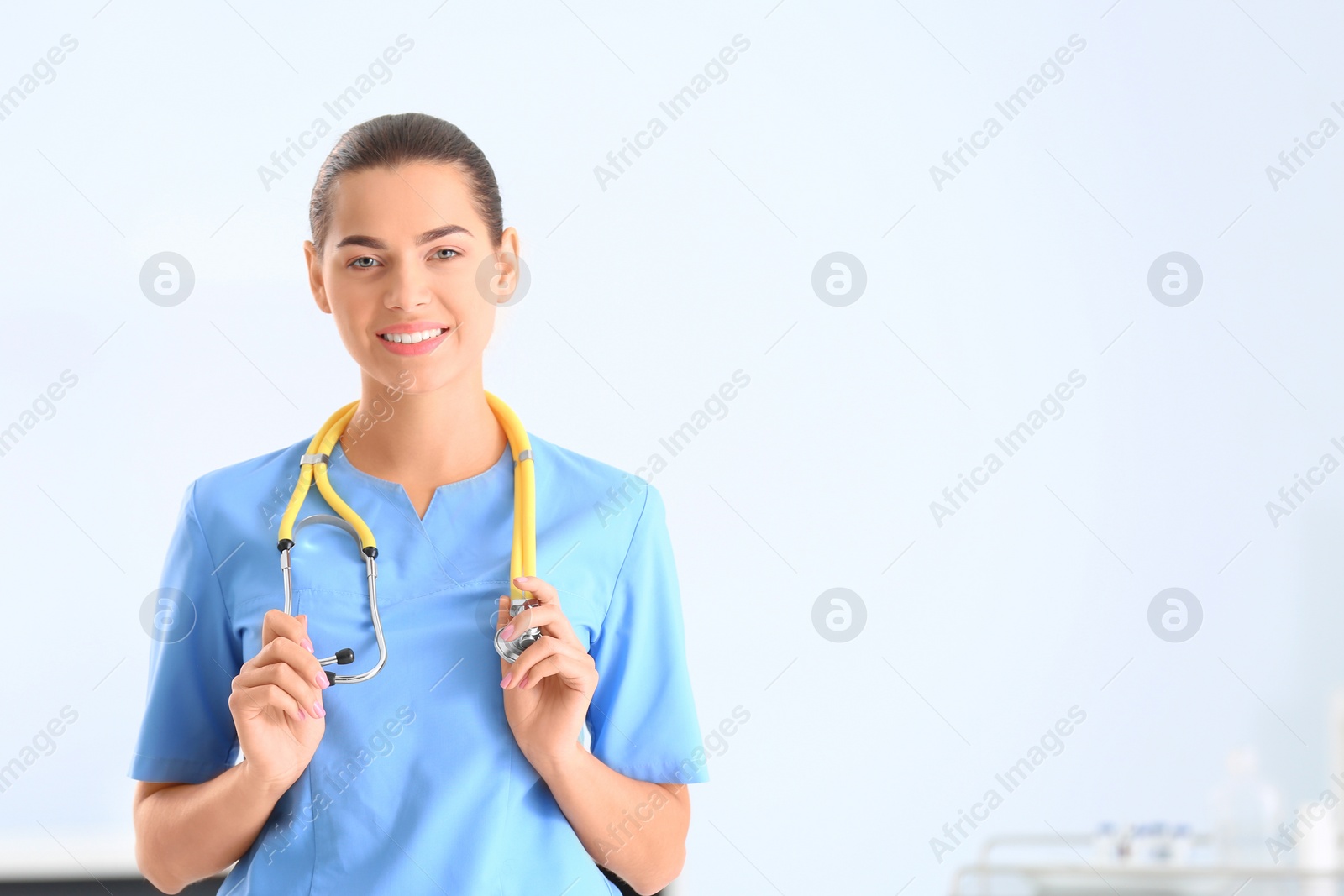 Photo of Portrait of young medical assistant with stethoscope in hospital. Space for text