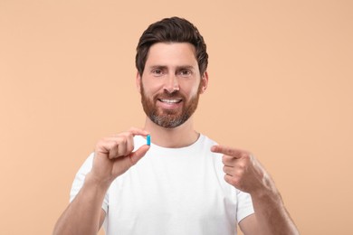 Handsome man with pill on beige background