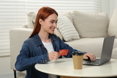 Photo of Happy woman with credit card using laptop for online shopping at home