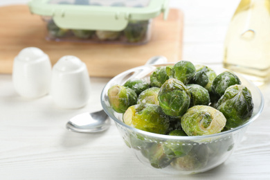 Photo of Frozen Brussels sprouts on white wooden table. Vegetable preservation