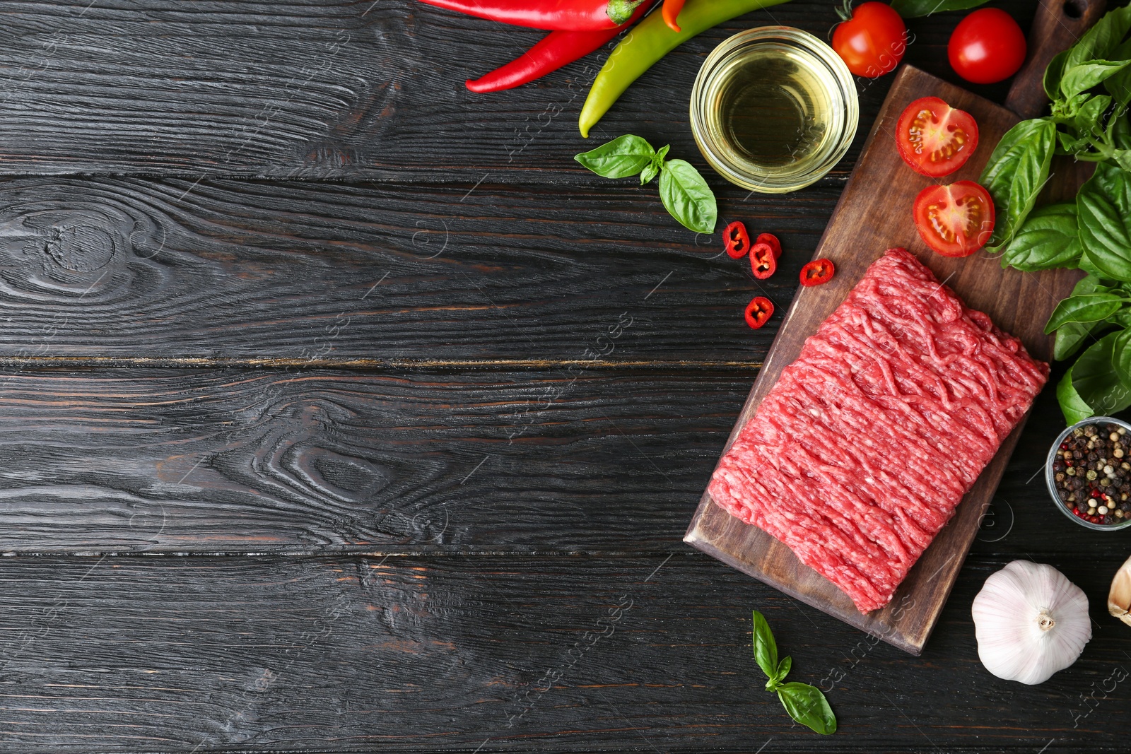 Photo of Flat lay composition with fresh raw minced meat on black wooden table. Space for text