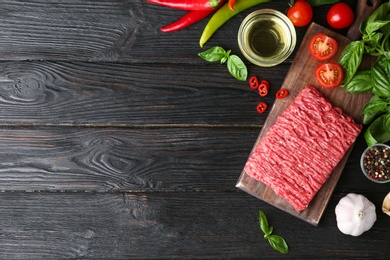 Photo of Flat lay composition with fresh raw minced meat on black wooden table. Space for text