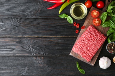 Flat lay composition with fresh raw minced meat on black wooden table. Space for text