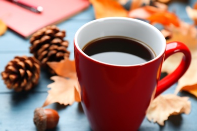 Photo of Cup of hot drink and leaves on blue wooden table, closeup. Cozy autumn atmosphere