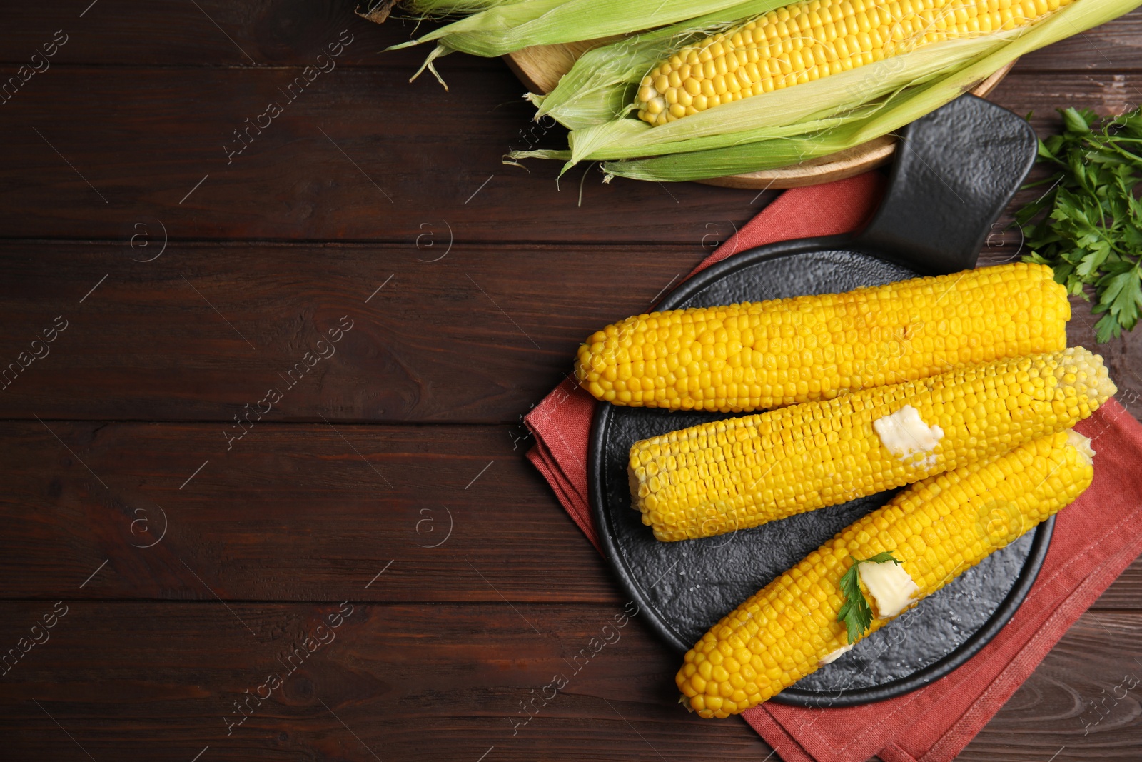 Photo of Fresh corn cobs with butter on wooden table, flat lay. Space for text