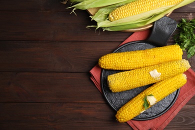 Photo of Fresh corn cobs with butter on wooden table, flat lay. Space for text