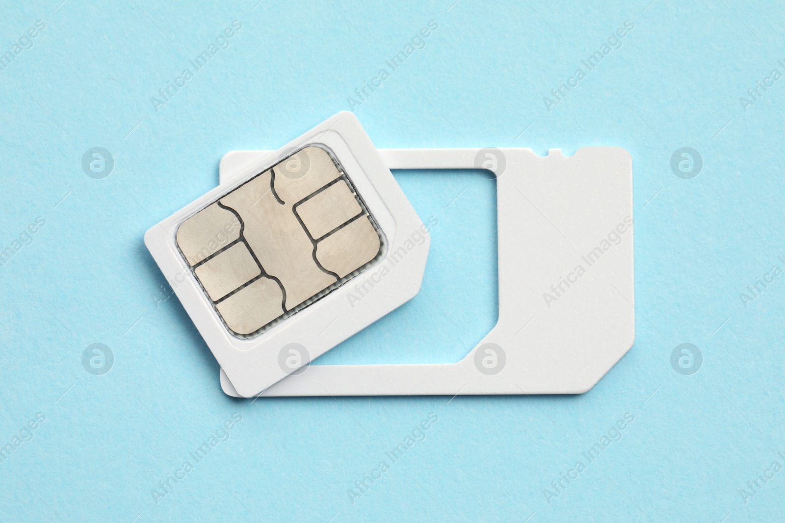 Photo of Modern SIM card on light blue background, top view