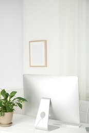 Office interior with houseplant and computer monitor on table