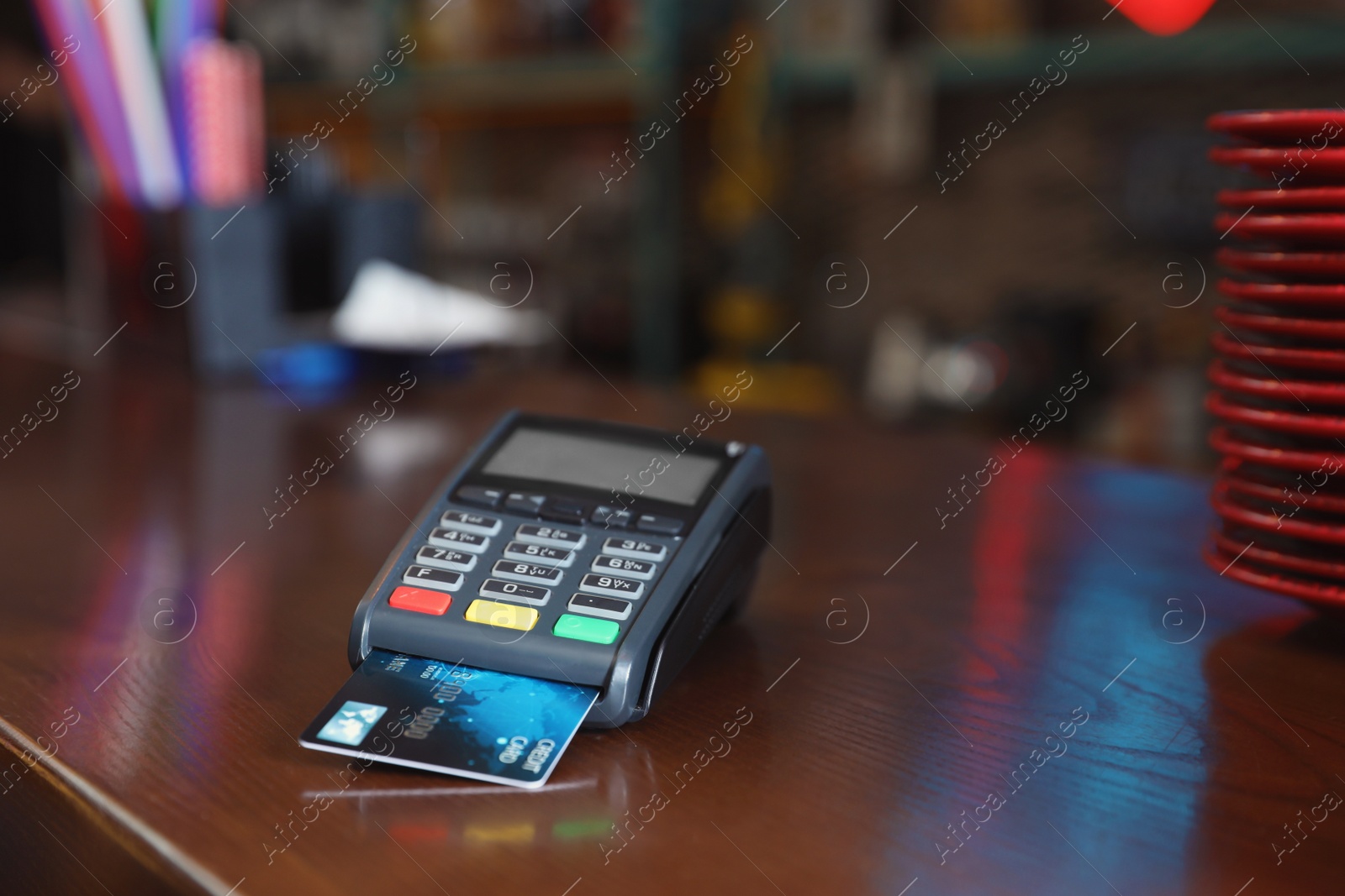 Photo of Credit card machine for non cash payment on wooden counter in cafe. Space for text