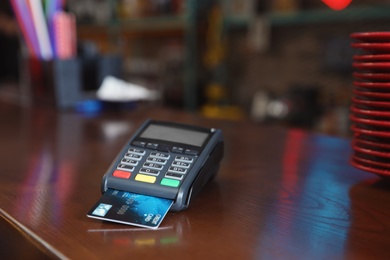 Credit card machine for non cash payment on wooden counter in cafe. Space for text