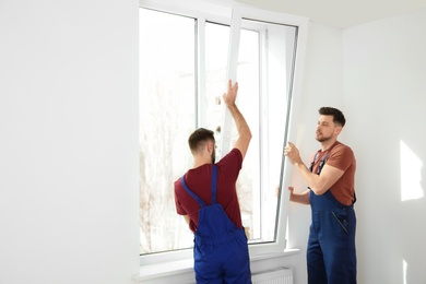 Photo of Construction workers installing plastic window in house