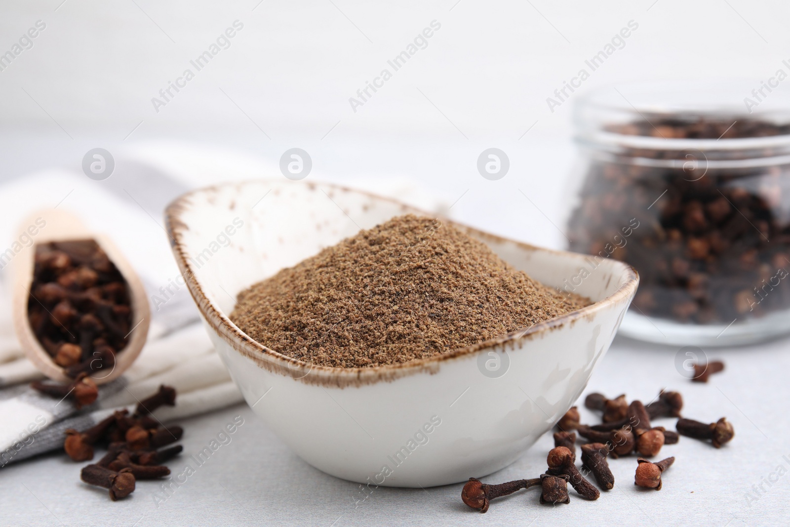 Photo of Aromatic clove powder and dried buds on light table, closeup