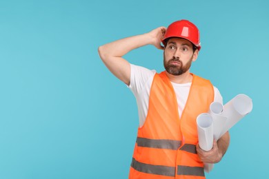 Photo of Confused architect in hard hat with drafts on light blue background, space for text