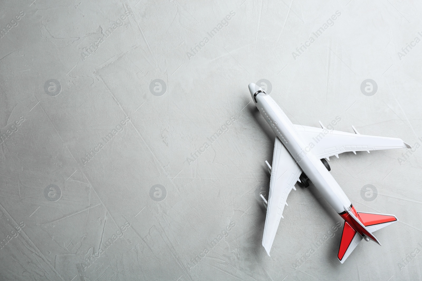 Photo of Toy airplane on grey stone background, top view. Space for text