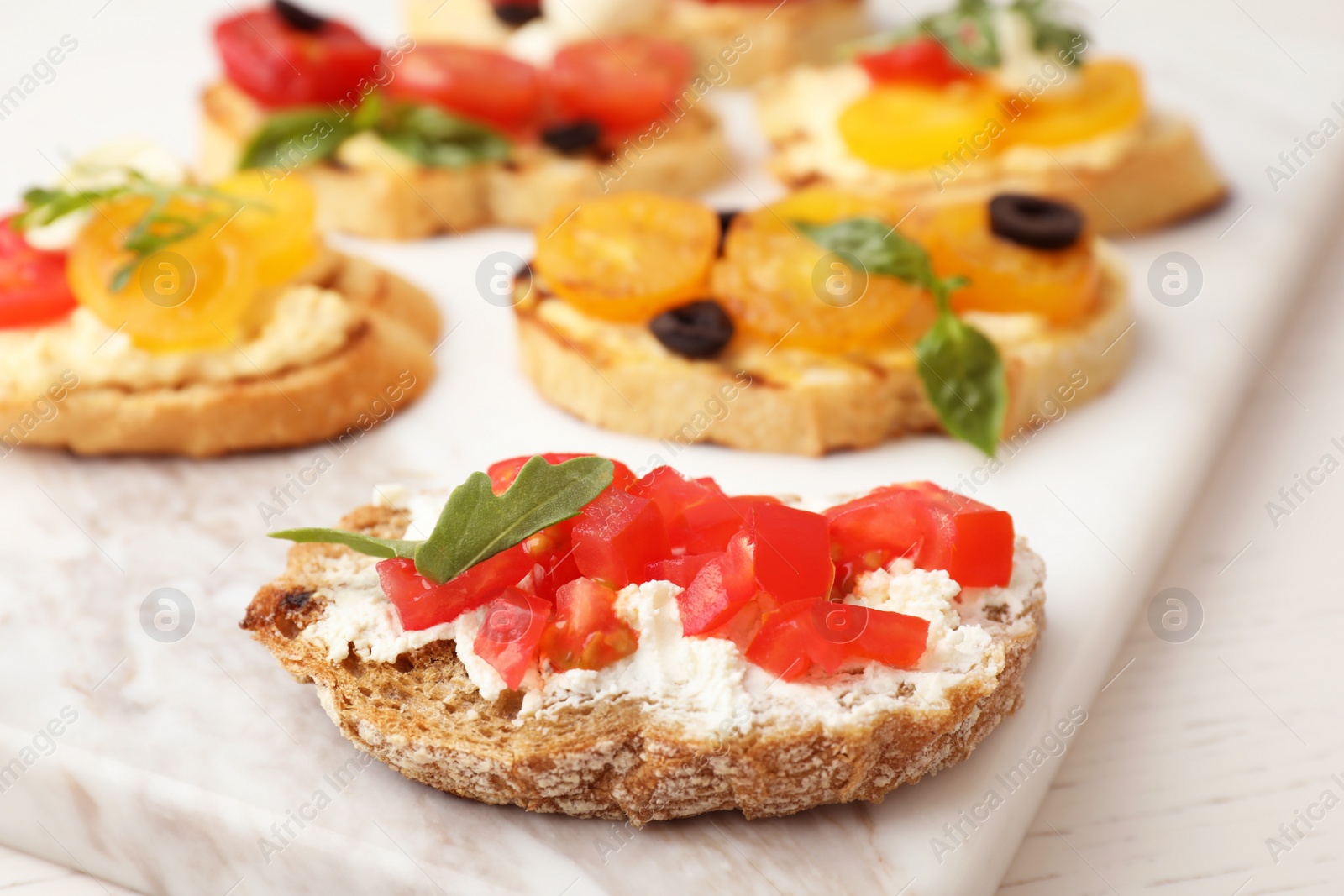 Photo of Delicious tomato bruschettas on marble board, closeup