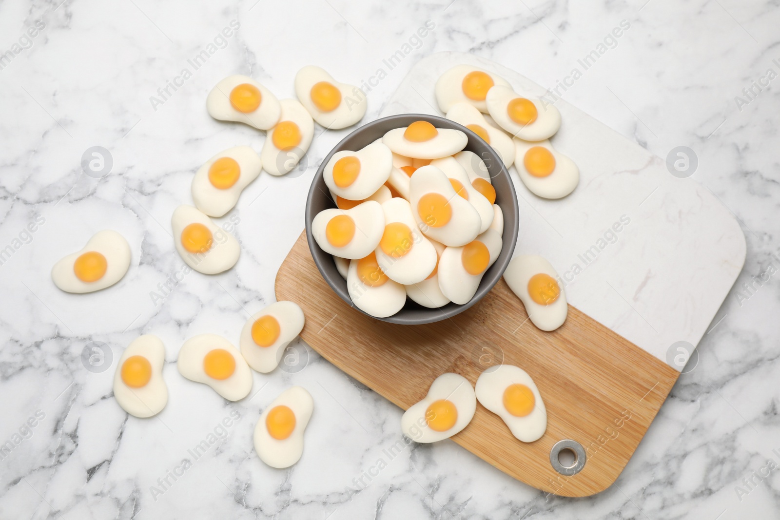 Photo of Delicious gummy fried eggs shaped candies on white marble table, flat lay