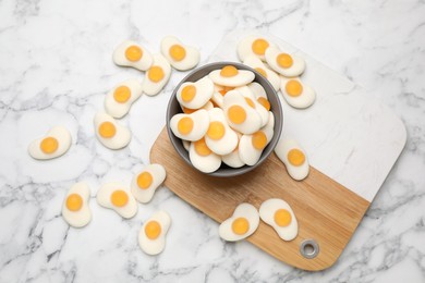 Delicious gummy fried eggs shaped candies on white marble table, flat lay